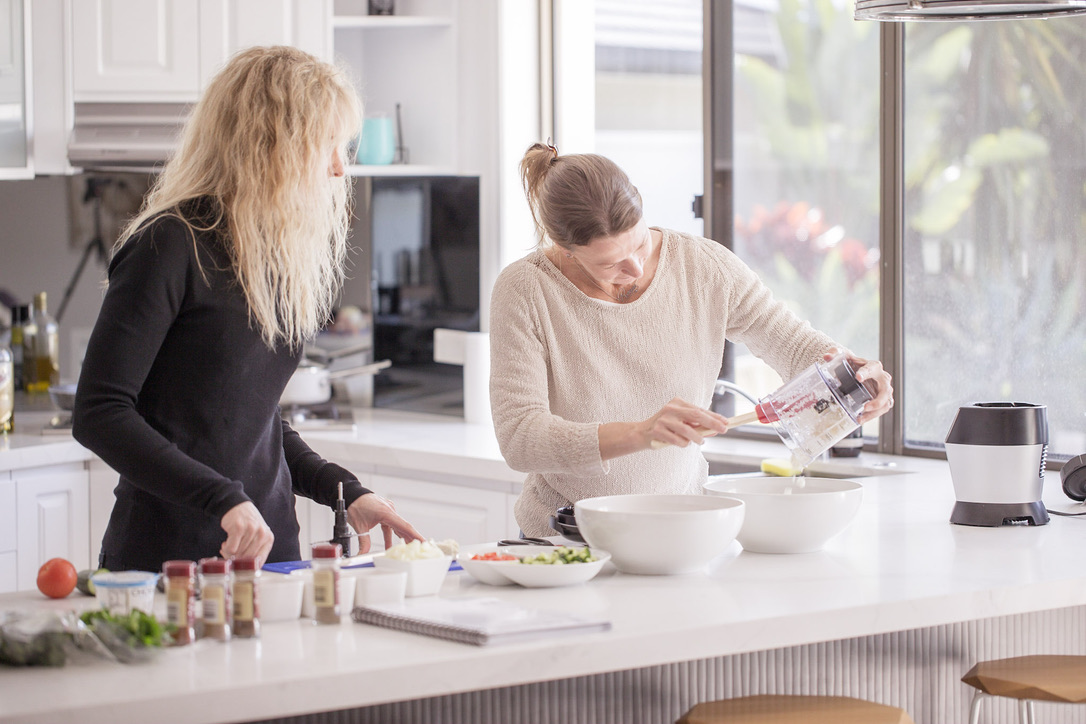 Preparing fresh food together Two women preparing fresh food together in a bright kitchen
